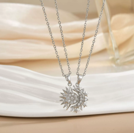 Duo de colliers Célunéa Cristal argentés, pendentifs soleil et lune sertis de pierres blanches étincelantes, présentés sur assiette blanche